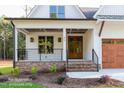 Charming home features a brick porch, black railings, and a natural wood front door at 12845 Mallard Rock Rd, Zebulon, NC 27597