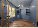 Stylish home office featuring beautiful blue walls, built in shelving, and hardwood flooring at 12845 Mallard Rock Rd, Zebulon, NC 27597