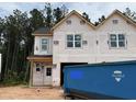 New two-story home under construction featuring newly-installed windows, black roof, and adjacent construction dumpster at 15 Calluna Dr, Clayton, NC 27520
