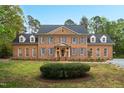 Beautiful two-story brick home featuring symmetrical design, dormer windows, shutters, and a well-manicured lawn at 2238 Lakeview Ter, Burlington, NC 27215