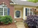 Close-up of front entrance with a decorative glass door, brick accents, and lush landscaping at 6673 Nc 96 W Hwy, Youngsville, NC 27596