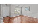 Light filled entryway features gleaming hardwood floors, a front door with sidelight and transom, and neutral colored walls at 104 Harvolly Dr, Holly Springs, NC 27540