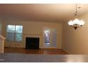 View of the living room with a fireplace, outdoor access, and a stylish chandelier providing a warm ambiance at 104 Sir Richard Ln, Chapel Hill, NC 27517