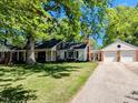 Exterior view of home with brick accents and a detached two-car garage, surrounded by mature trees and green lawn at 107 Forest Rd, Oxford, NC 27565