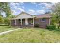Beautiful brick home featuring classic shutters, a welcoming porch, and landscaped front yard at 1303 Cherry Dr, Burlington, NC 27215