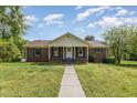 Charming brick home with a manicured lawn and inviting front porch under a beautiful sky at 1303 Cherry Dr, Burlington, NC 27215