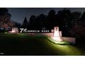 Night view of illuminated Magnolia Park entrance sign, with manicured landscaping and elegant lighting at 231 Yellow River Way, Garner, NC 27529