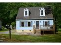 Inviting light blue house showcasing dormer windows, a quaint porch, and vibrant greenery at 2315 George Anderson Dr, Hillsborough, NC 27278