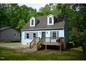 Charming light blue home featuring a cozy front porch, dormer windows, and a lush green surrounding landscape at 2315 George Anderson Dr, Hillsborough, NC 27278