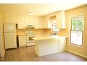 Bright kitchen with white cabinets, laminate countertop, a window, and modern vinyl flooring at 2315 George Anderson Dr, Hillsborough, NC 27278