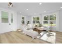 Bright living room with light wood floors, white sofas, chairs, curtains, area rug, and large windows at 3018 White Rail Dr, Fuquay Varina, NC 27526