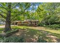 Traditional home with a brick exterior, covered carport, and a charming porch, nestled among mature trees and greenery at 424 Raleigh View Rd, Raleigh, NC 27610
