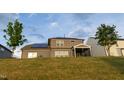 Back exterior view of a home with solar panels and a grassy backyard hill at 428 Parlier Dr, Apex, NC 27523
