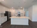 Modern kitchen with white cabinets, stainless steel appliances, quartz countertops and island with sink at 521 Morning Light Dr, Angier, NC 27501