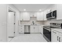 Updated kitchen with white cabinetry, marble countertops, stainless appliances, and a modern backsplash design at 620 Wexford Dr, Raleigh, NC 27603