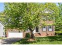 Traditional brick home featuring a two-car garage, a well-maintained lawn, and mature trees at 1007 Grandover Dr, Durham, NC 27713