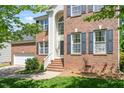 Close-up view of a brick home entrance with steps, white railings, and dark shutters at 1007 Grandover Dr, Durham, NC 27713