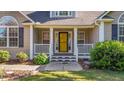 Inviting front entrance with a bright yellow front door, flanked by well-maintained landscaping and a small porch at 106 Contender Dr, Clayton, NC 27520