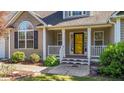Inviting front porch with white railings and a bright yellow front door, flanked by well-maintained landscaping at 106 Contender Dr, Clayton, NC 27520
