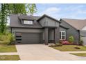 Well-maintained gray home featuring a two-car garage, professionally landscaped front yard, and modern design at 109 Imagine Way, Pittsboro, NC 27312