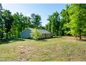 A big backyard, surrounded by many trees, with a view of the back of the home at 116 Shawnee Dr, Louisburg, NC 27549