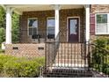 Charming front porch with brick facade, black iron railings, and comfortable seating area with accent door at 144 Elk Stone Trl, Garner, NC 27529