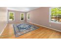 Sunny bedroom with hardwood floors, three windows, and a stylish area rug at 1506 Ephesus Church Rd, Chapel Hill, NC 27517