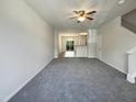 Open concept living room with soft gray carpet, ceiling fan, and abundant natural light from sliding glass doors at 1610 Oxleymare Dr, Raleigh, NC 27610