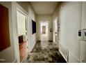 A hallway with white walls, and tile flooring, leading to several rooms, including a bathroom in the distance at 211 Webb St, Roxboro, NC 27573