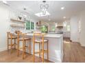 Bright kitchen features island seating, stone countertops, decorative shelves, and stainless steel appliances at 3009 Hillmer Dr, Raleigh, NC 27609