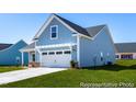 Charming blue home featuring a two-car garage and well-manicured front lawn and inviting curb appeal at 517 W Brocklyn St # 63P, Benson, NC 27504