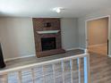 Spacious living room with hardwood floors, a brick fireplace, and an open doorway to another room at 710 E Azalea Ct, Fuquay Varina, NC 27526