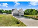 Inviting white two-story home featuring a gray garage door, landscaped yard, and long driveway at 72 Glenwood Pl, Kenly, NC 27542