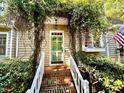 Inviting entrance with a green front door, brick steps, white railing and lush greenery at 1712 Briarforest Pl, Raleigh, NC 27615
