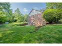 Expansive backyard featuring lush greenery, a brick retaining wall and a shed at 2457 Millbrook Dr, Haw River, NC 27258