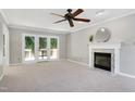 Spacious living room featuring a fireplace, ceiling fan, and glass doors leading to the deck at 300 Silvercliff Trl, Cary, NC 27513
