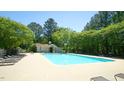 A large community pool with lounge chairs and a pool house surrounded by lush trees at 4024 Claret Ln, Morrisville, NC 27560