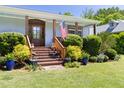 Inviting front porch adorned with lush greenery and a charming wooden door and American flag at 416 Mitchell St, Hillsborough, NC 27278