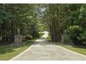 Long private driveway lined with trees, leading to the beautiful stone and brick home at 5901 Charleycote Dr, Raleigh, NC 27614