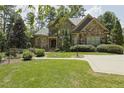 Stunning stone home featuring lush landscaping, mature trees, and a walkway leading to the entrance at 5901 Charleycote Dr, Raleigh, NC 27614
