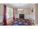 Elegant dining room with a floral rug, large window, stylish chandelier, and classic wainscoting at 612 Lakeview Ave, Wake Forest, NC 27587
