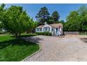 Inviting single-story home with a gravel driveway and landscaped front yard surrounded by mature trees under a clear sky at 713 E Whitaker Mill Rd, Raleigh, NC 27608