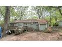 Back exterior of a cozy home with a wooden deck, green siding, surrounded by lush greenery and mature trees at 7312 Ray Rd, Raleigh, NC 27613