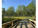 Scenic view of a paved greenway trail with wooden bridge, surrounded by lush trees and greenery at 908 Kensley Grove Lane St #69, Fuquay Varina, NC 27526