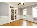 Bright room featuring hardwood floors, French doors, wainscoting, neutral walls and two large windows at 105 Kenmont Dr, Holly Springs, NC 27540