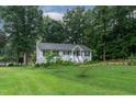 Scenic view of single story home with well-manicured lawn and mature trees, close to the lake at 106 Palomino Cv, Louisburg, NC 27549