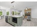 Open-concept kitchen with modern island, stainless steel appliances, and adjacent stone fireplace in living area at 107 Seminole Dr, Louisburg, NC 27549