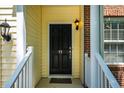 A black front door with a charming light fixture welcomes you to this home with yellow siding and brick accents at 11 Piccadilly Ct, Durham, NC 27713