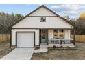 Charming exterior featuring white vertical siding, a cozy porch, and a convenient one-car garage at 1101 Ridge Rd, Roxboro, NC 27573