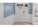 Bright entryway boasts wainscoting detail, a transom window, and elegant decor for a welcoming ambiance at 116 Alumroot Rd, Holly Springs, NC 27540
